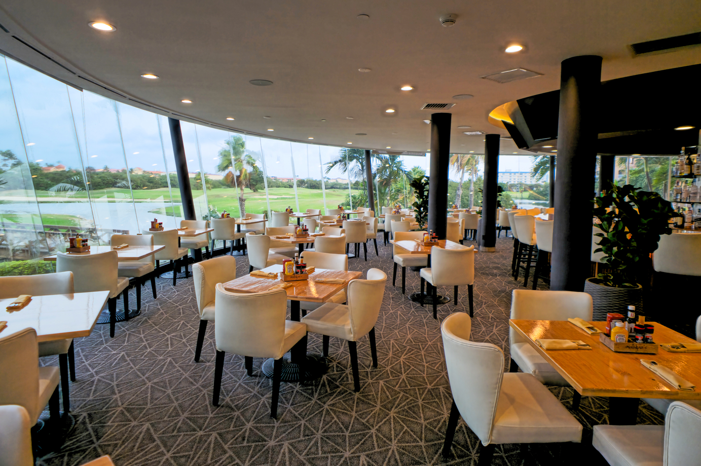 Mulligans Interior Interior view of the recently updated Mulligan's Bar & Restaurant with modern white chairs, warm wood accents, and an expansive view of the golf course.